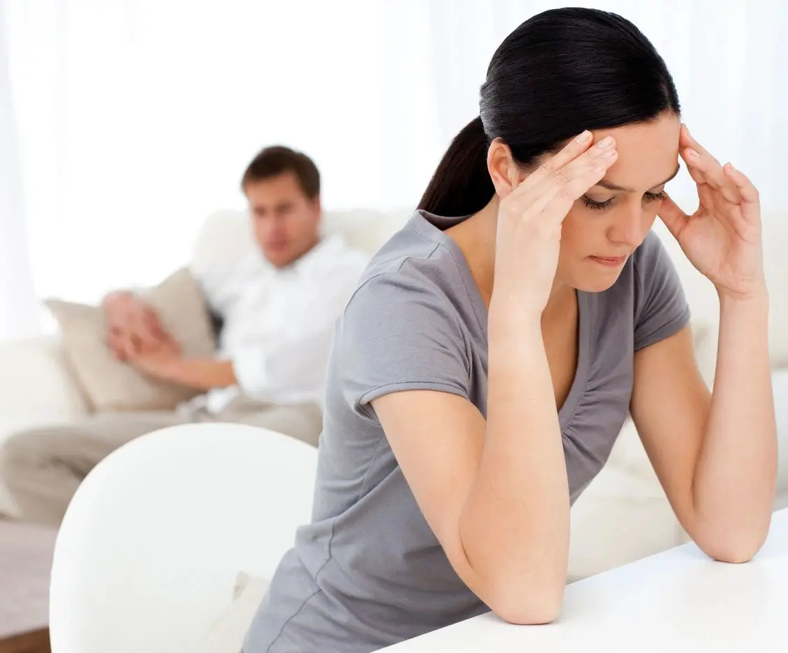 A woman sitting in front of another man.